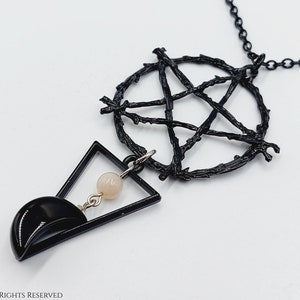 Op de afbeelding: Zwarte ketting met een pentagram hanger gemaakt van gedraaide takken. De hanger is bevestigd aan een geometrische driehoek met een kleine roze kraal die eraan hangt.