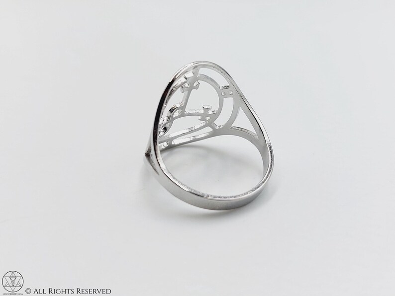 May include: A silver ring with a geometric design. The ring is open in the front and has a delicate, intricate pattern.