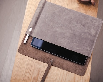 May include: A brown leather tablet case with a flap that folds over to protect the screen. A white stylus is tucked into a slot on the side of the case.