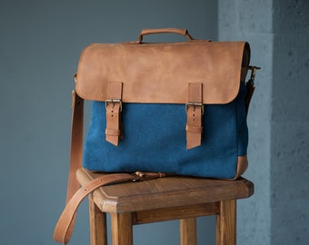 May include: A brown leather and blue canvas messenger bag with a long adjustable strap. The bag has two buckles on the front and a top handle.