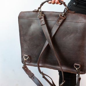 May include: A brown leather briefcase with adjustable straps that can be worn as a backpack. The briefcase has a top handle and metal hardware.