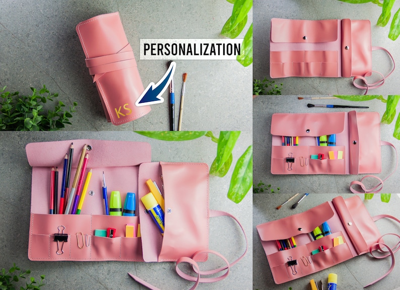 May include: A pink roll-up stationery organiser featuring multiple interior pockets and slots for pens, pencils, and office supplies. The exterior displays the text PERSONALISATION and the gold-coloured initials KS on the front flap.