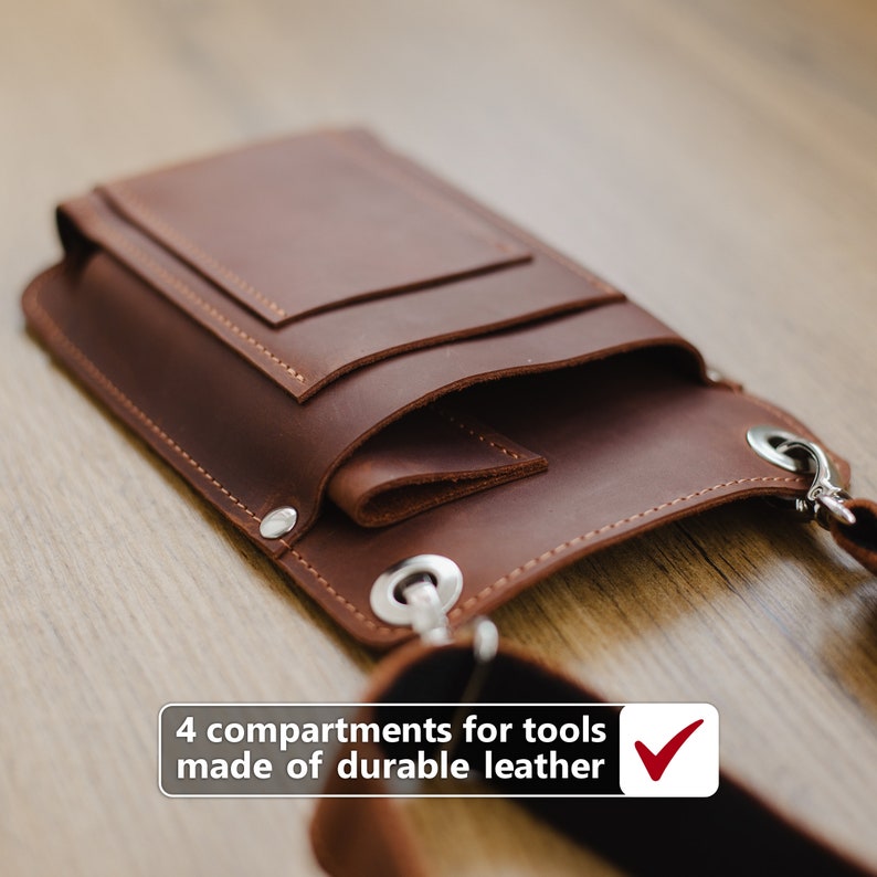 May include: A brown leather tool bag with four compartments and a shoulder strap. The bag is made of durable leather and has a checkmark next to the text "4 compartments for tools made of durable leather".