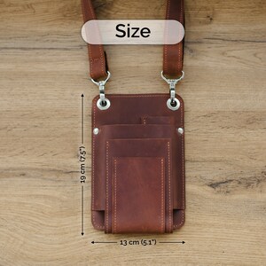 May include: Brown leather phone pouch with multiple pockets and a strap. The pouch measures 19 inches tall and 13 inches wide.