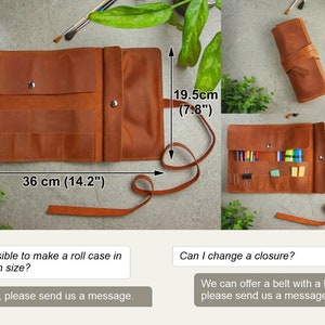 May include: A brown leather roll case featuring multiple interior pockets, a snap button closure, and a long wrap-around strap. The case measures 36 cm in width and 19.5 cm in height. It is shown both open with stationery and rolled shut.