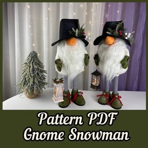 May include: Two white gnome snowmen with black hats, green mittens, and red and white striped legs. The snowmen are holding lanterns and standing on a white surface. The text "Pattern PDF Gnome Snowman" is at the bottom of the image.