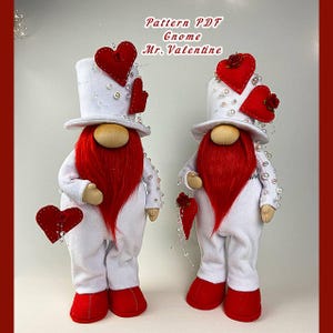 May include: Two white felt gnomes with red beards and hats decorated with red hearts and white beads. The text "Pattern PDF Gnome Mr. Valentine" is at the top of the image.