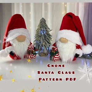 May include: Two red and white Santa Claus gnomes with white fur trim and a white beard. The gnomes are holding red and white striped gift boxes. The gnomes are sitting on a white surface in front of a small green Christmas tree. The text "Gnome Santa Claus Pattern PDF" is written below the gnomes.