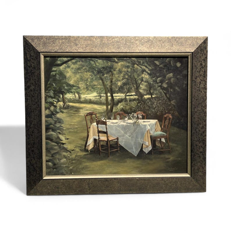May include: A framed painting depicts a serene outdoor dining scene. A table set with dishes and flowers is covered with a white tablecloth, surrounded by wooden chairs. The painting is set in a lush garden with trees and greenery.