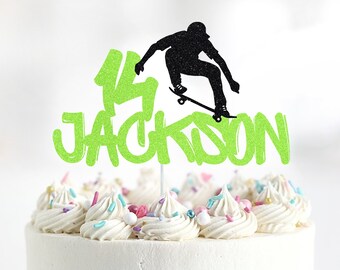 May include: Green and black glitter cake topper with a silhouette of a person skateboarding and the text "14 JACKSON".