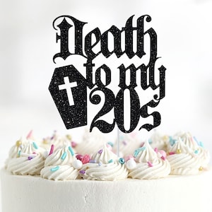 Peut inclure: Décor de gâteau noir pailleté avec le texte "Death to my 20s" en police gothique. Un cercueil noir pailleté avec une croix blanche est à côté du texte.