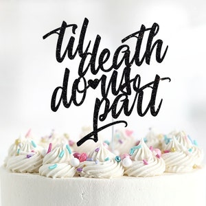 May include: Black glitter cake topper with the text "Til death do us part" with a small heart symbol in the text. The topper is on top of a white cake with colorful sprinkles.