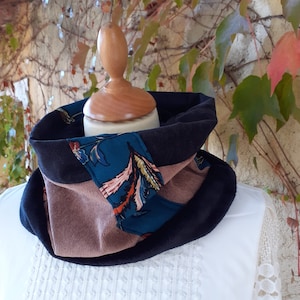 Peut inclure: Un tour de cou en tissu noir, marron et bleu sarcelle avec un motif floral. Le tour de cou est plié et présenté sur un mannequin.