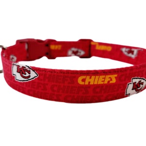 May include: Red dog collar featuring a white and yellow Kansas City Chiefs logo and the word "CHIEFS" repeated on the collar.