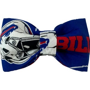 May include: Blue and white bow tie with a football helmet and the word "Bills" in red.