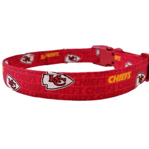 May include: Red dog collar featuring a Kansas City Chiefs logo and the word "CHIEFS" in yellow.