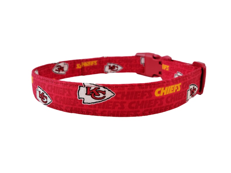 May include: Red dog collar featuring a Kansas City Chiefs logo and the word "CHIEFS" in yellow.