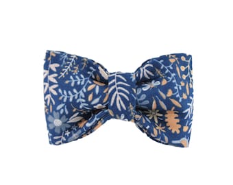 Puede incluir: Una pajarita azul marino con un estampado floral en tonos blancos, celeste y beige. Este accesorio clásico es adecuado para diversas ocasiones. La tela parece ser de algodón o un material similar. La pajarita es un accesorio elegante.