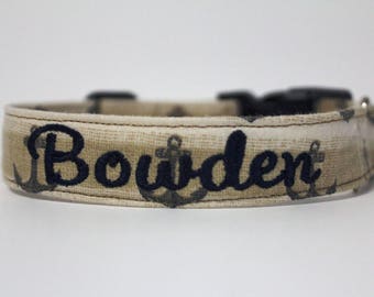 May include: A beige dog collar with a navy blue anchor print and the name "Bowden" embroidered in navy blue.
