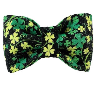 May include: A black bow tie with a green shamrock pattern. The shamrocks are in shades of green and yellow.