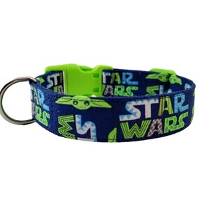 May include: A navy blue dog collar featuring the text "STAR WARS" in white and green, along with images of Grogu. The collar has a lime green plastic buckle and a silver metal D-ring.