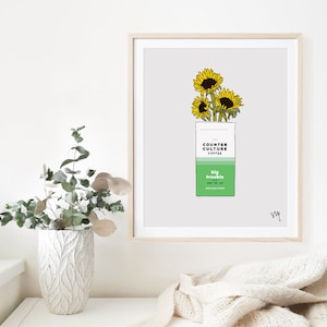 May include: A digital illustration of a coffee bag with sunflowers on top. The bag is green and white and says "Counter Culture Coffee" and "Big Trouble" on it.