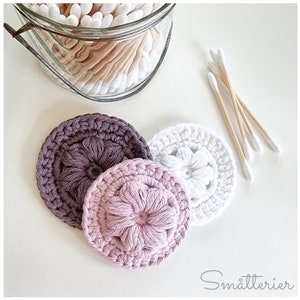 May include: Three crocheted cotton rounds in shades of purple, pink, and white. Each round has a raised flower design in the center.