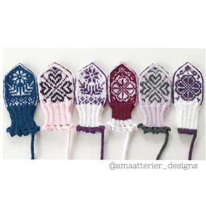 Puede incluir: Cinco guantes sin dedos de punto con diferentes patrones de colores. Los guantes son blancos, rosas, azules, burdeos y grises. Los patrones son geométricos y presentan copos de nieve y corazones. Los guantes están todos alineados en una superficie blanca. El texto "@smaatterier_designs" está en la parte inferior de la imagen.