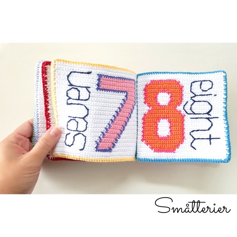 May include: A crocheted book with colorful numbers and the words "seven" and "eight" on each page. The book is made with white yarn and has a blue, orange, yellow, and red border.