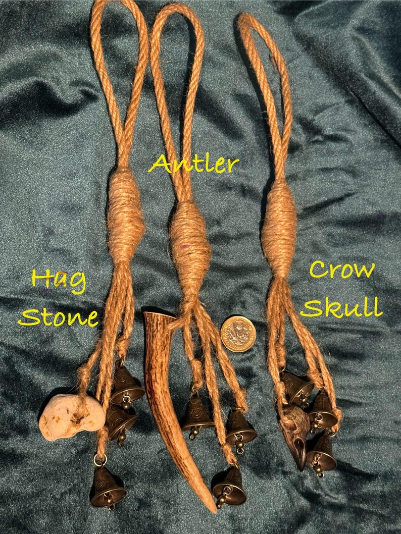 Pode incluir: Tr&ecirc;s amuletos de corda marrom com sinos. Os amuletos s&atilde;o etiquetados como "Hag Stone", "Antler" e "Crow Skull". Cada amuleto tem um objeto diferente preso &agrave; extremidade da corda. O amuleto Hag Stone tem uma pedra marrom claro presa. O amuleto Antler tem uma galhada marrom presa. O amuleto Crow Skull tem uma pequena caveira de corvo marrom presa.