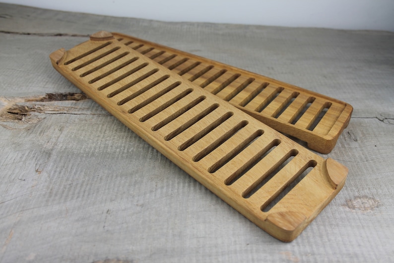 May include: Two wooden bread boards with a slatted design. The boards are made of light brown wood and are stacked on top of each other.