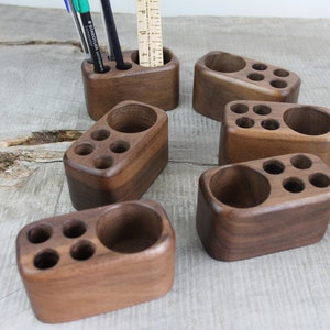 May include: Six wooden desk organizers with multiple compartments for pens, pencils, and other office supplies. The organizers are made of dark brown wood and have a smooth, polished finish.