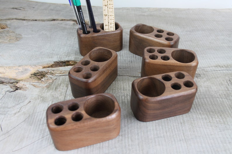 May include: Six wooden desk organizers with multiple compartments for pens, pencils, and other office supplies. The organizers are made of dark brown wood and have a smooth, polished finish.