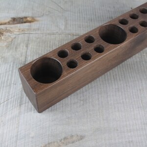 May include: A wooden organizer with multiple compartments of varying sizes. The organizer is made of dark brown wood and has a smooth finish.