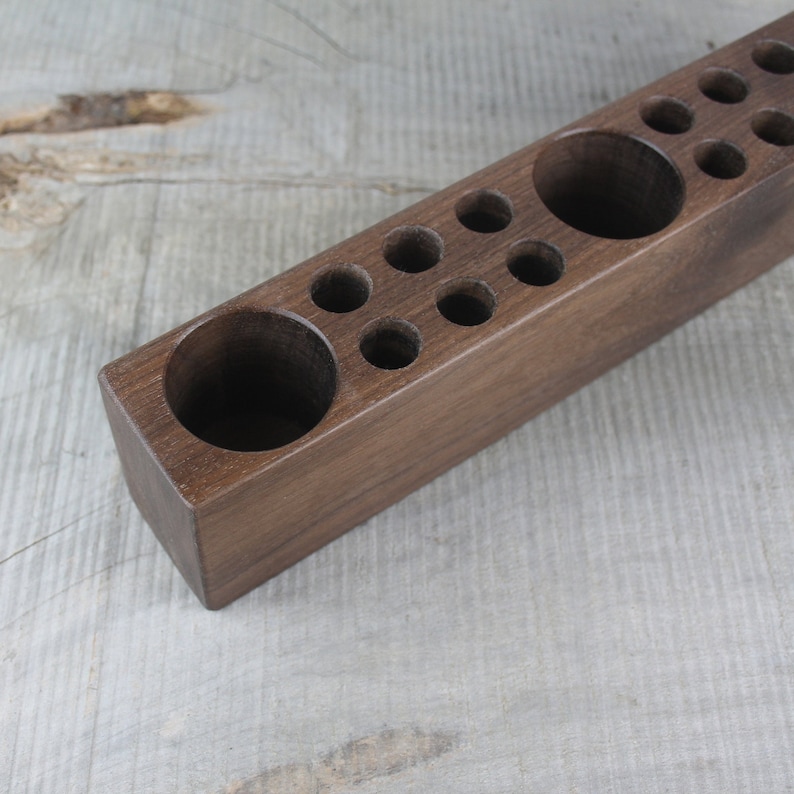 May include: A wooden organizer with multiple compartments of varying sizes. The organizer is made of dark brown wood and has a smooth finish.