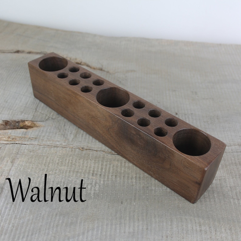 May include: A wooden organizer with multiple round holes for storing small items. The organizer is made of walnut wood and has a natural finish.