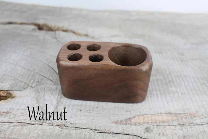 May include: A wooden desk organizer with four slots and a larger compartment. The organizer is made of walnut wood and has a natural finish.