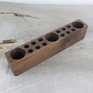 May include: A wooden organizer with multiple compartments of varying sizes. The organizer is made of dark brown wood and has a rectangular shape.