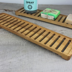 May include: Two wooden soap dishes with slatted bottoms. The dishes are made of light brown wood and are designed to allow water to drain.