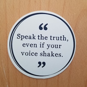 May include: White round sticker with a black border and black text that reads "Speak the truth, even if your voice shakes."