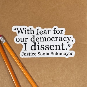 May include: A white sticker with black text that reads "With fear for our democracy, I dissent."  The text is attributed to Justice Sonia Sotomayor.