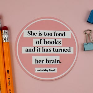 May include: A pink round sticker with the quote "She is too fond of books and it has turned her brain." by Louisa May Alcott.