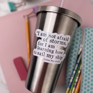 May include: A stainless steel tumbler with a white sticker that reads "I am not afraid of storms, for I am learning how to sail my ship."  The quote is attributed to Louisa May Alcott.