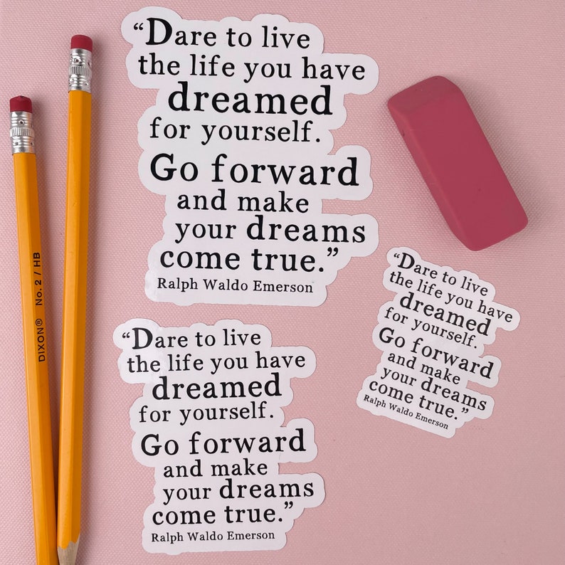 Op de afbeelding: Twee witte stickers met zwarte tekst op een roze achtergrond. De tekst op de stickers luidt "Durf te leven het leven waarvan je hebt gedroomd voor jezelf. Ga vooruit en maak je dromen waar." De tekst wordt toegeschreven aan Ralph Waldo Emerson.
