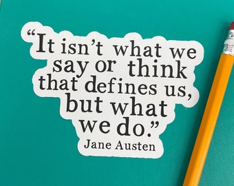 May include: A white die-cut sticker featuring the black text: "It isn't what we say or think that defines us, but what we do." followed by the name "Jane Austen" in a serif font, positioned next to a yellow pencil with a silver metal ferrule.