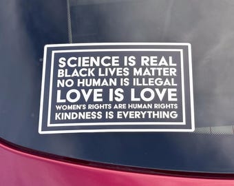 May include: A black and white sticker with the text "SCIENCE IS REAL, BLACK LIVES MATTER, NO HUMAN IS ILLEGAL, LOVE IS LOVE, WOMEN'S RIGHTS ARE HUMAN RIGHTS, KINDNESS IS EVERYTHING."