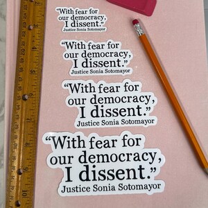 May include: Four white stickers with black text that reads "With fear for our democracy, I dissent." and "Justice Sonia Sotomayor".