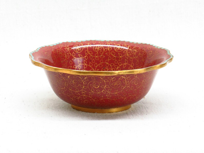 May include: A red bowl with a gold and turquoise rim and a gold floral pattern.