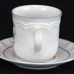 May include: White ceramic teacup and saucer with a blue floral design and a blue trim.