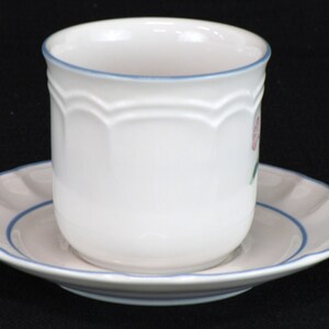 May include: A white ceramic teacup and saucer set with a blue rim and a pink floral design.